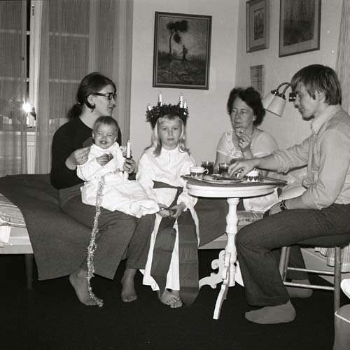 Två barn med luciakläder fikar med tre vuxna, 1970.
