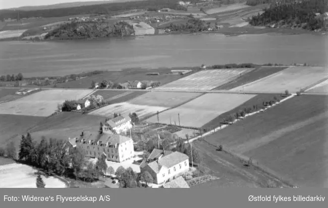 Haugetun ungdomsskole tatt mot Soliveien og Visterflo. Noen gårdsbruk og boliger ses på andre siden av vannet.