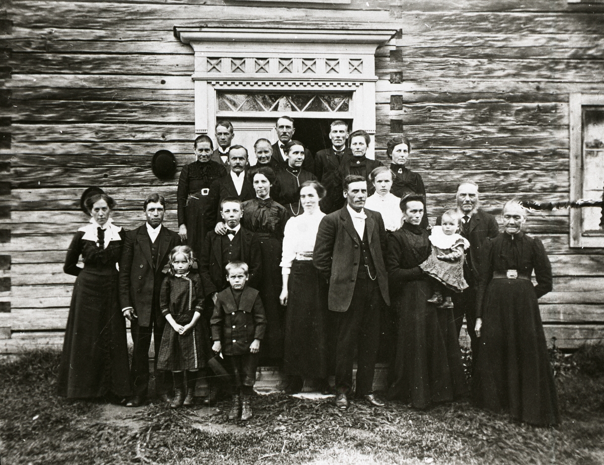Män, kvinnor och barn samlade framför dörrarna till ett hus.