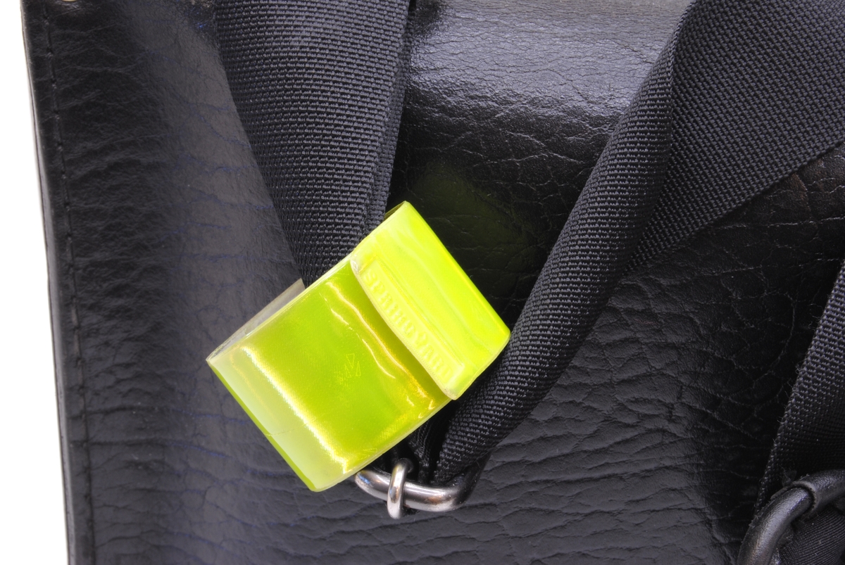 Ett grönt reflexband som rullar ihop sig.

Sitter fast på väskans axelrem.