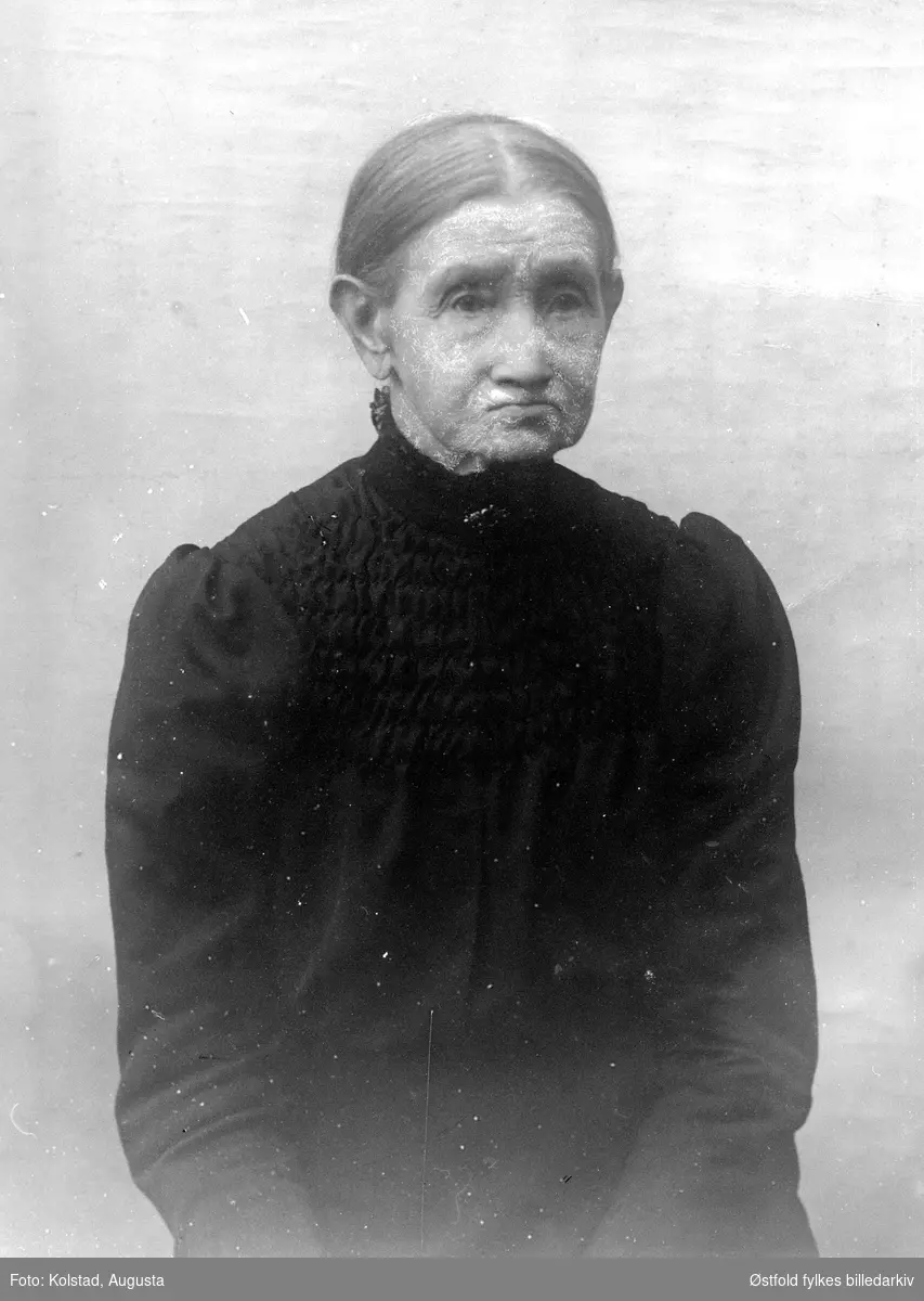 Portrett av Helene Kolstad (1828-1926), mor til fotografen, gårdbrukerkone på gården søndre Kolstad i Askim. På bildet er hun enke. Bodde sine siste år på Olavsrud, Korsegård sammen med sine døtre, Se ØFB.AKO.00001.