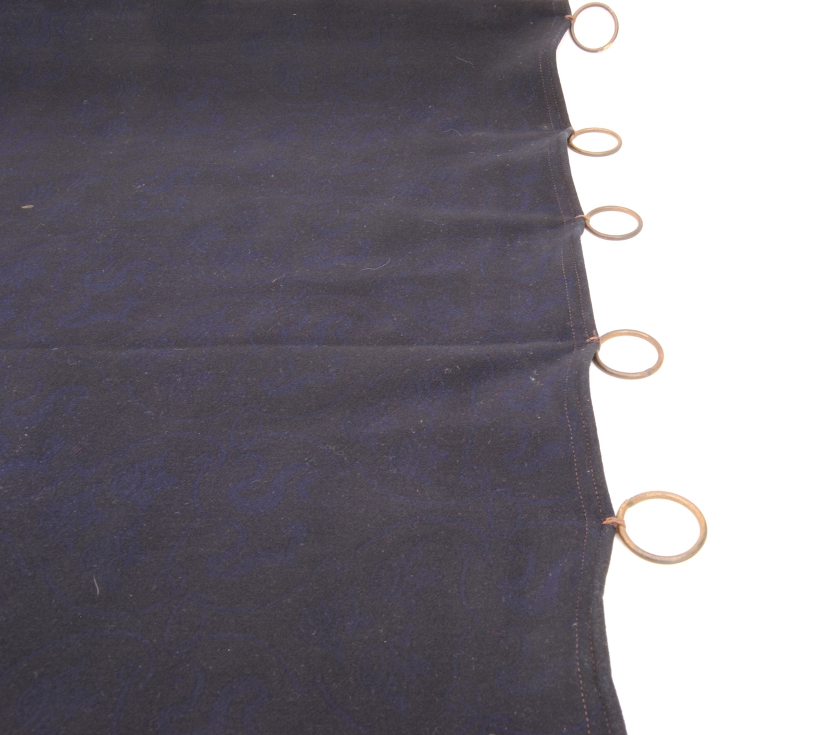 En gardin av fint kläde, med blått mönster på svart botten. Mönstret består av slingrande linjer som bildar fält som fylls växelvis av SJ:s initialer eller tre kronor.
På tygets avigsida är färgerna omvända.

Gardinen har en fåll med dubbelsöm upptill, nedtill och på sidorna är fållen sydd med enkelsöm. Alla kanter är invikta en gång. Gardinen har mässingsringar fastsydda i den övre fållen för upphängning.