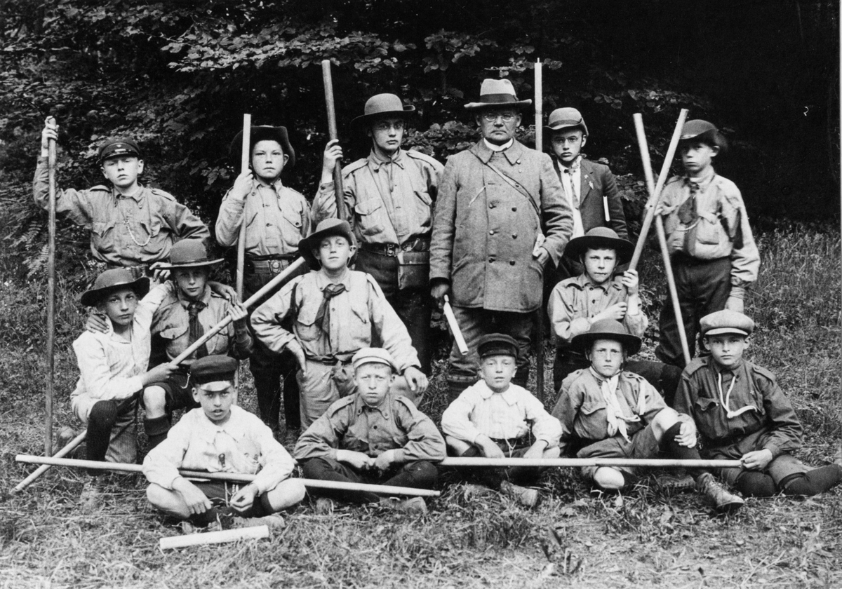 Gruppbild på 14 scouter i Alingsås scoutkår under ledning av rektor G A Bohlin vid läroverket.
Alingsås scoutkår startade 1911 och lades ned 1922.
2:a från vänster i främsta raden är Gusten Hallberg.