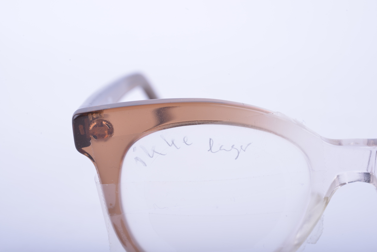 Brille i hvit og brun plast med frostet glass på høyre side. Glass med hull for å sette inn ulike linser på venstre side.