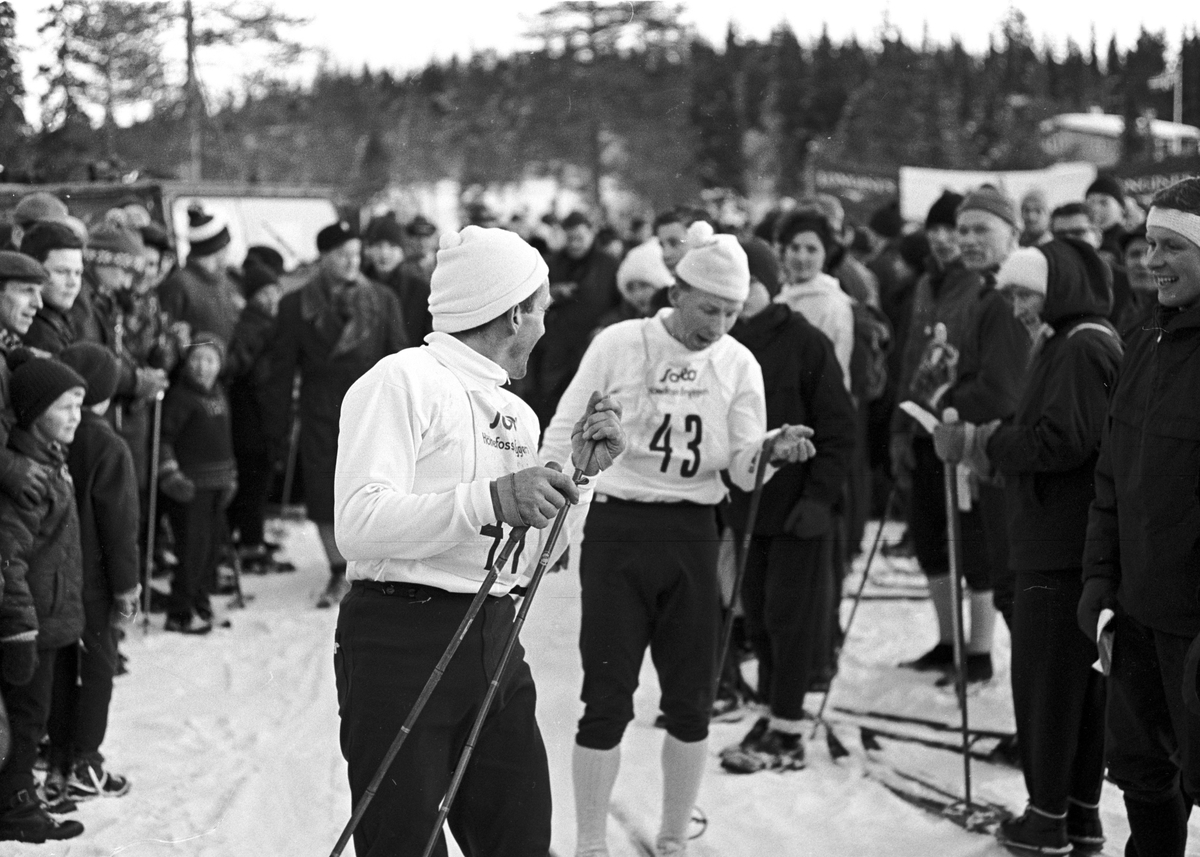 Mange tilskuere rundt to skiløpere, Ringkollrennet. Fotografert 13. januar 1964.