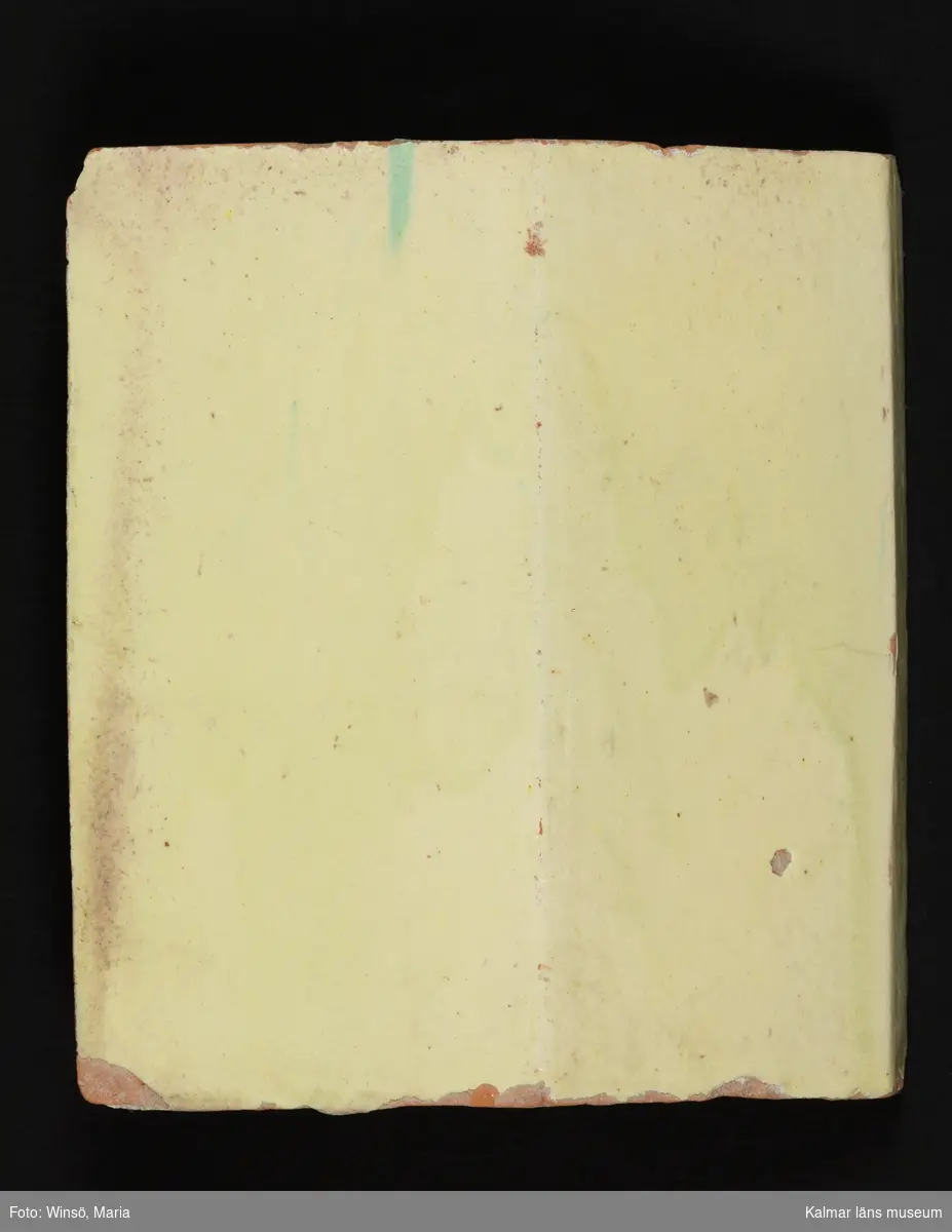 KLM 38928. Kakel. Till kakelugn. Svagt gulgrön blyglasyr på röd lergodsskärv. Drejad rump.

Förteckning över samtliga kakel, med mått inom parentes, gjord i samband med inventering 1997:  
:1.  3 st. fasadkakel         (26x21x5 cm)
     2 st.  -"-                    (26,5x21,5x6 cm)
     1 st.  -"-                    (26,5x21x5,5 cm)
     1 st.  -"-                    (26,5x20x6 cm)
     2 st.  -"-  1/2 lod       (26,5x16,5x5 cm)
     3 st.  -"-  1/2 lod       (26,5x10x5,5 cm)
:2. 12 st. hörnfasad        (23x13x6 cm)
:3. 4 st. krönsims           (13x21,5x5 cm)
     1 st.  -"-                   (13x10,5x4 cm)
     1 st.  -"-                   (20x25x5 cm)
     1 st.  -"-                   (20x17x5 cm)
     1 st.  -"-                   (13,5x11x4 cm)
:4. 1 st. hörnkrönsims    (13x25x5 cm)
     1 st.  -"-                   (13x17,5x5 cm)
:5. 7 st. simser               (6x21,5x4,5 cm)
     1 st.  -"-                   (6x18x4 cm)
:6. 2 st. hörnsimser        (6x15x3 cm)
:7. 5 st. fotsimser           (14,5x21,5x5 cm)
     1 st.  -"-                   (14,5x15,5x5 cm)
:8. 4 st. hörnfotsimser    (14,5x20x5,5 cm)
:9. 45 st. fragment