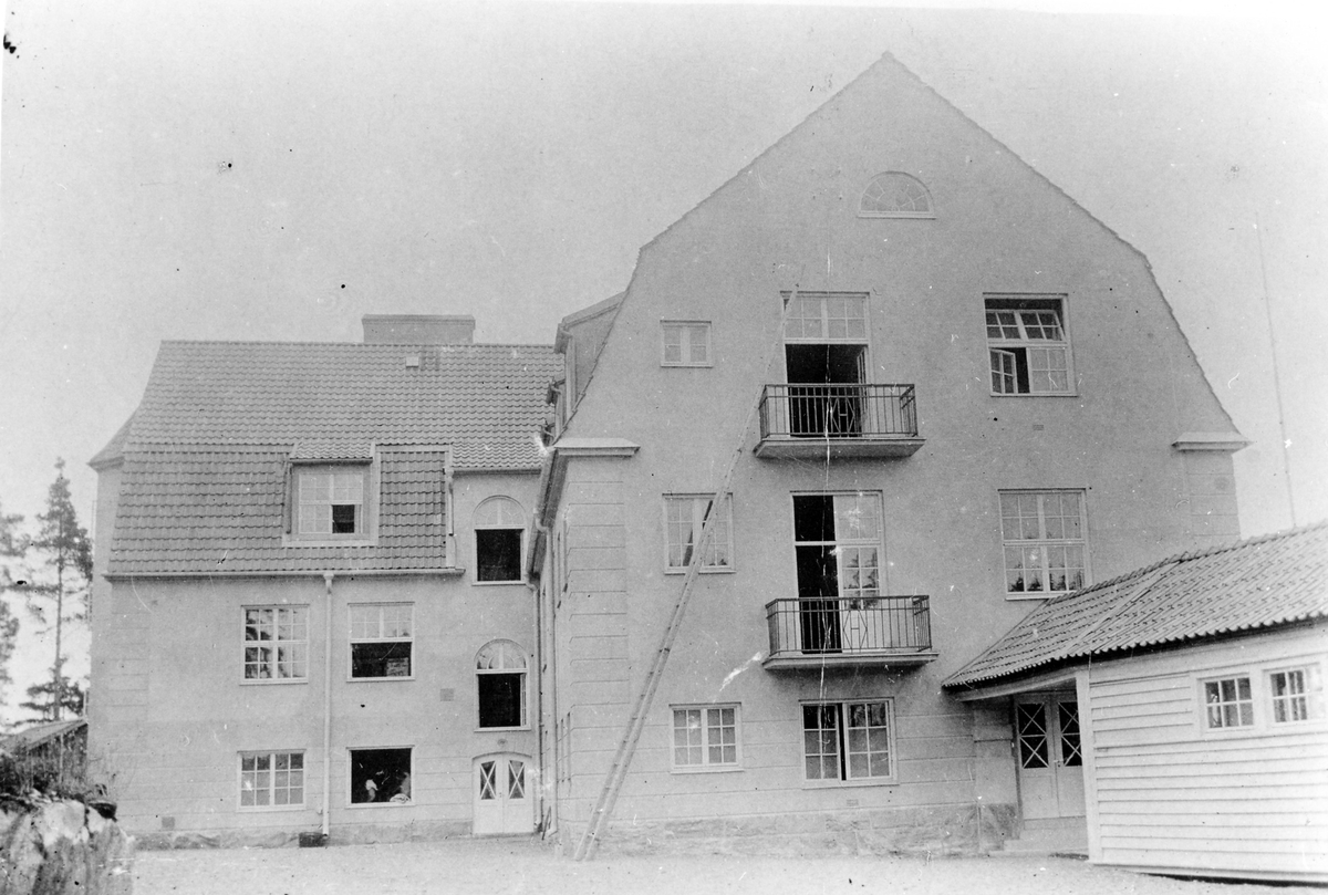 Bolltorps Sanatorium fotograferat från bakgården av treplansbyggnaden. Flera fönster är öppna och en lång stege ses sträcka sig till den översta balkongen på byggnades högra del. Byggdes 1917 och är idag ett bostadshus.