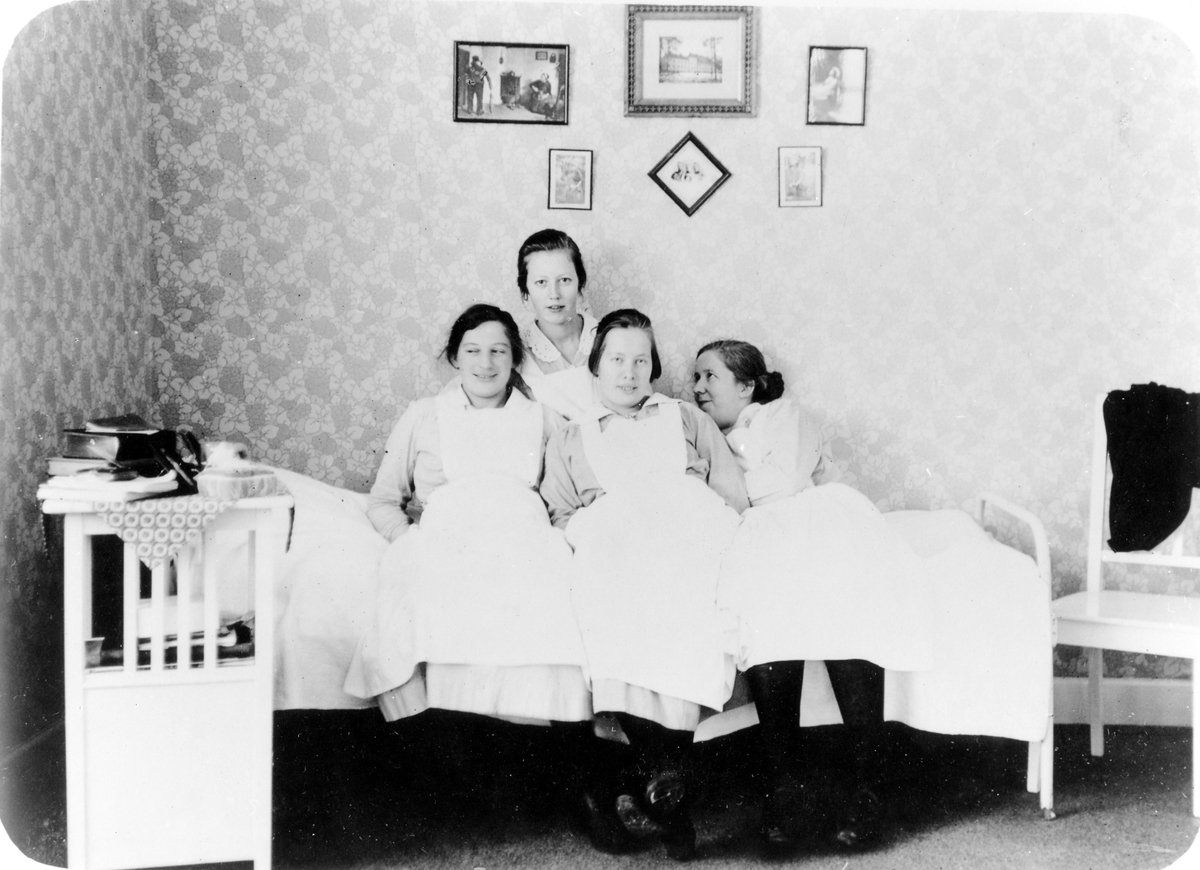 4 kvinnliga sjuksköterskor på Alingsås lasarett sitter på en säng i en sjuksköterskebostad.