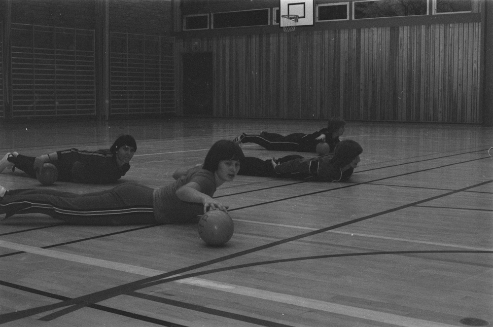 Trimtreff i Mosjøen. I gymsalen på Kippermoen eller Gymnaset. Kvinner og menn som gjør gymnastikk med ball ledet av instruktør.
