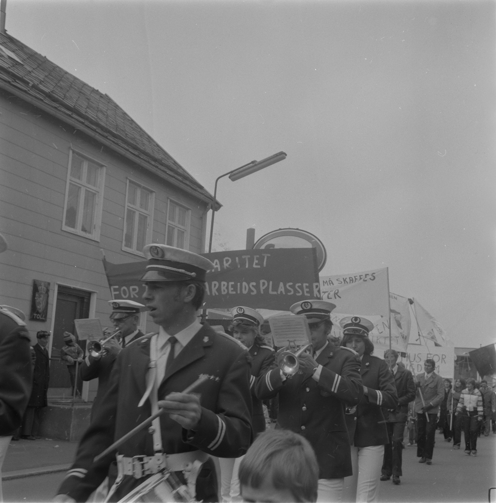 Hornmusikken Fram. 1.Mai-tog i Strandgata menn som bærer paroler. I bakgrunnen Tollbua.