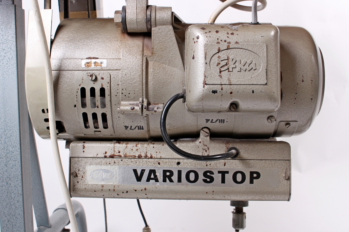 Symaskin med avtagbar arbeidslampe. Symaskinen er festet til et arbeidsbord og brukt hos Jonas Øglænd. Bruk: 1970-1979.