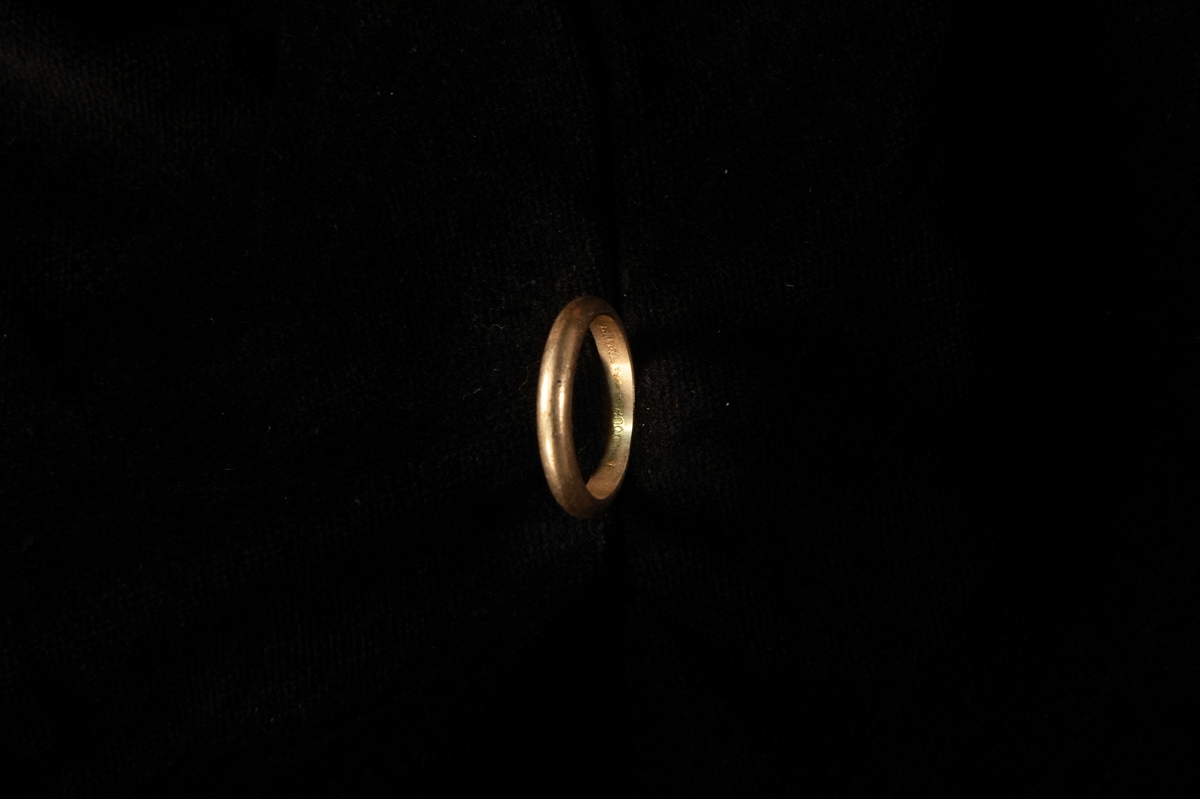 Fingerring av gulddouble, liggandes i en rund smyckesask med lock. Asken har ett marmorerat mönster, svart med roströd botten. Locket är rostrött med små inpräglade streck. Eventuellt hör inte de olika askdelarna till varandra från början.