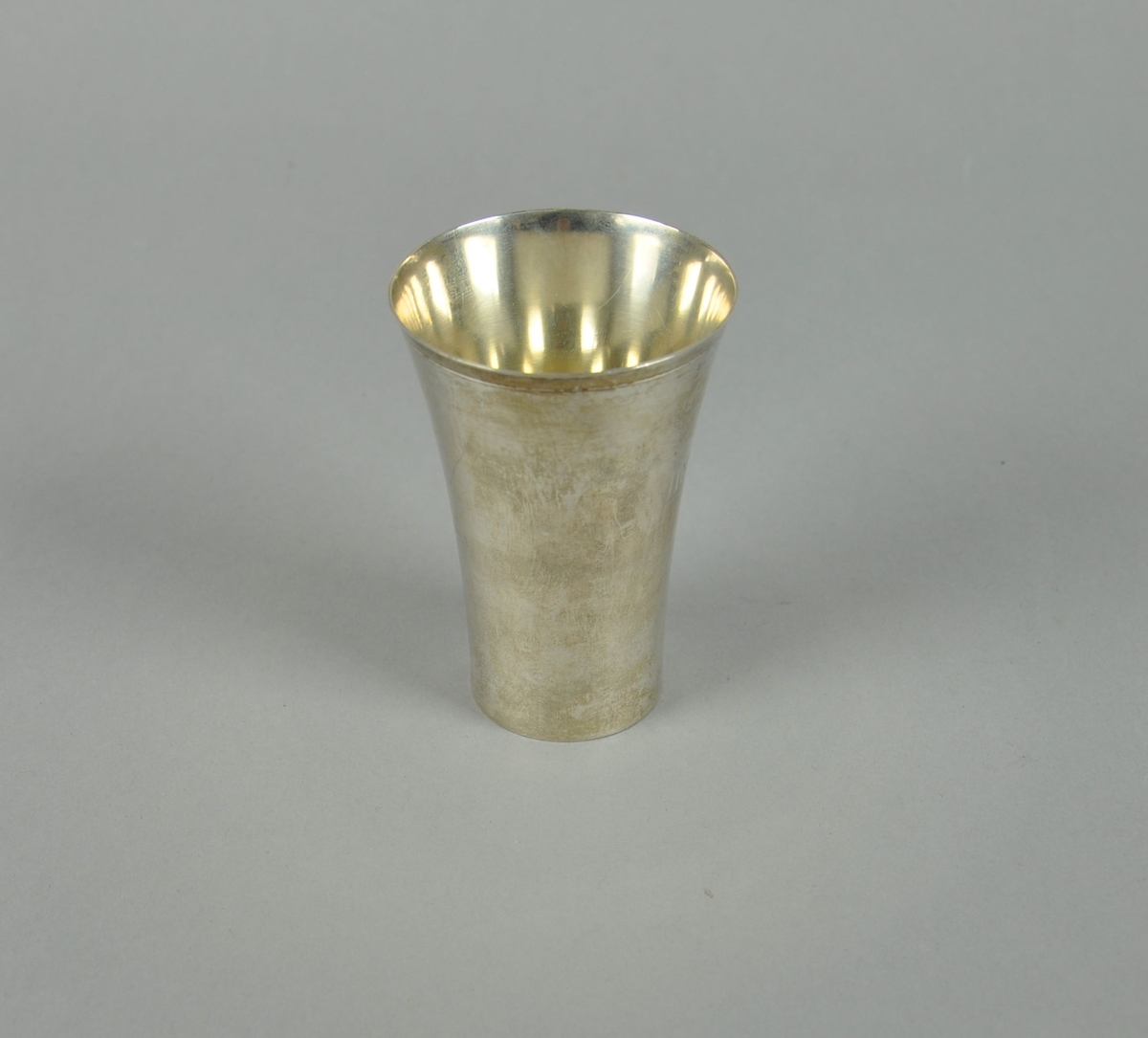 Pokal av sølv. Pokalen har sylindrisk form med utvidelse mot toppen.