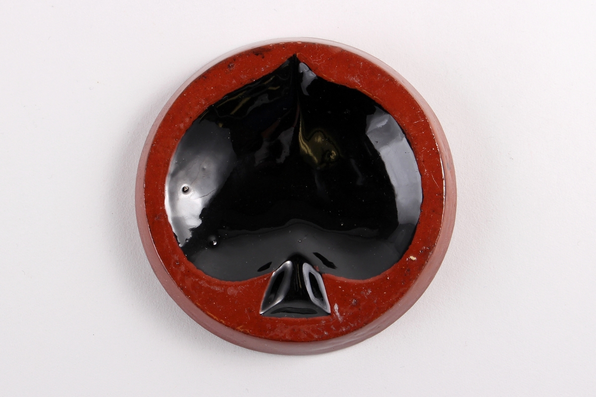 Rundt og lite askebeger dekorert med sort spar symbol brukt på spillkort.