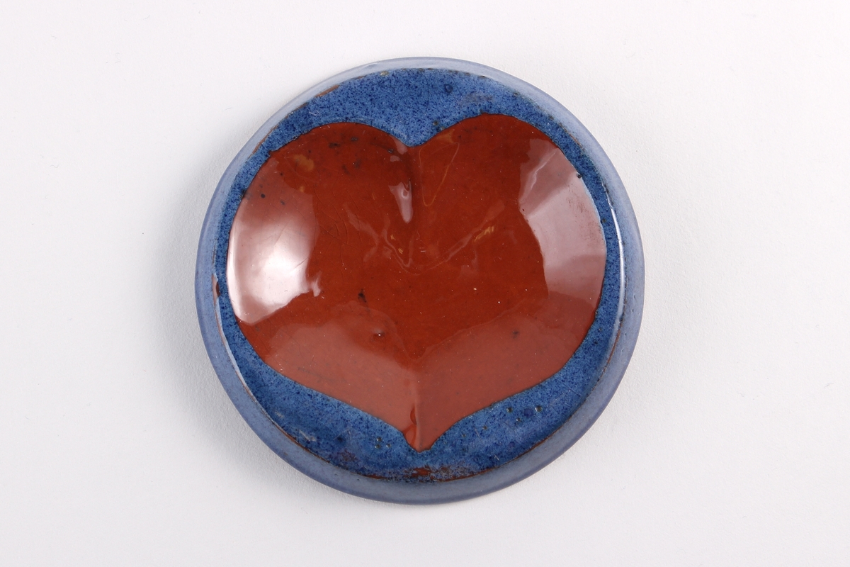 Rundt og lite askebeger med blå kant og med keramikkfarget hjerter symbol brukt på spillkort.