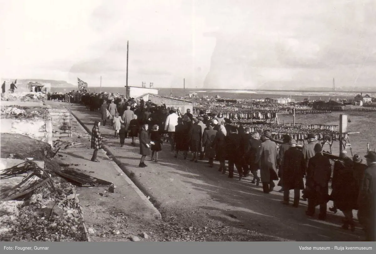 17. maitog i Vadsø 1945. Antatt fra Nyborgveien med krigsruiner og fiskehjell i bakgrunn.
