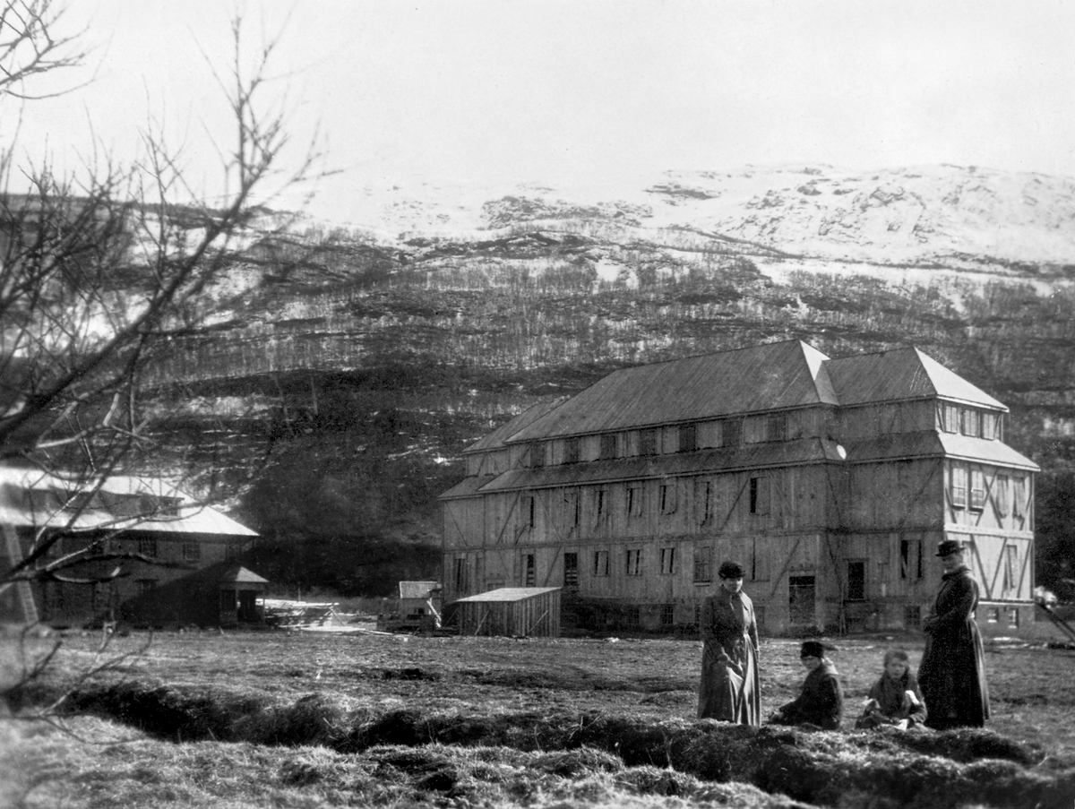 Lærerskolen på Nesna under bygging. Tre kvinner i kåper og hatter og ei jente i forkant.