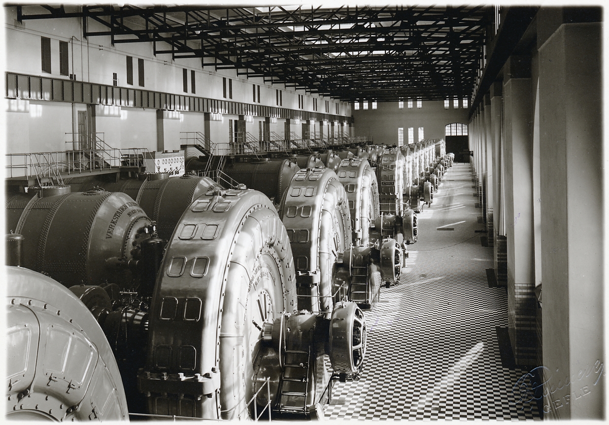 Interiörbild av turbiner i maskinsalen.
Trollhättans kraftstation kallas även Olidans kraftverk.
Olidestationen är den äldsta bland de av staten byggda och ägda vattenkraftsanläggningarna. 1906-års riksdag tog utbyggnadsbeslutet, och arbetet startade samma år. Stationen uppfördes i 3 steg, varav de 4 första togs i drift 1910. Ytterligare 4 aggregat ingick i den andra utbyggnadsetappen som gjordes 1912-1914. Den tredje etappen om 5 aggregat slutfördes 1918-1921.