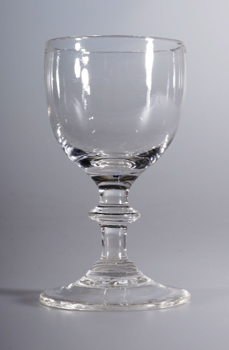 Stettglass, blåst i tre deler, med klokke, stett med skive og konveks fotplate. Brutt pontemerke/puntelmerke under. Kan være blåst på Gjøvik glassverk (1807-1843)