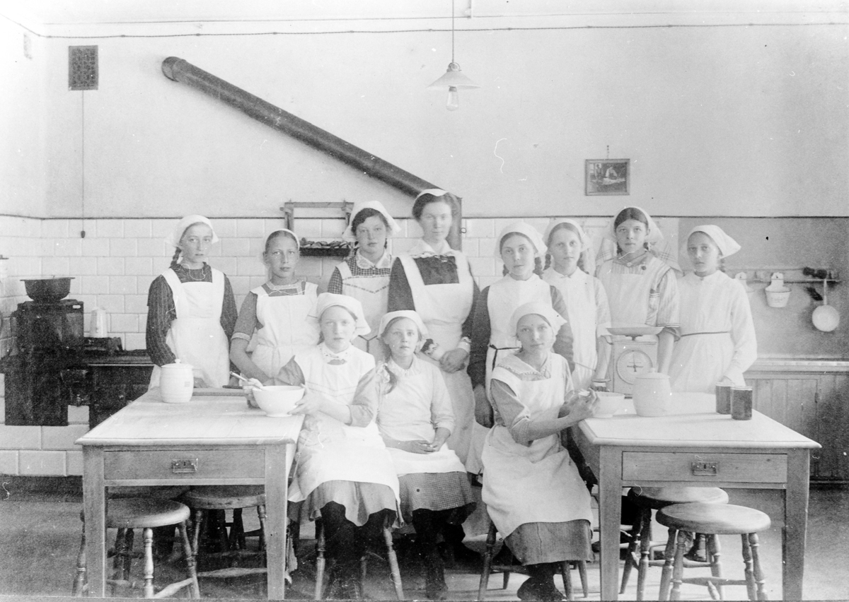 En lärarinna med en grupp flickor på en matlagningslektion i ett skolkök på okänd skola i Alingsås.