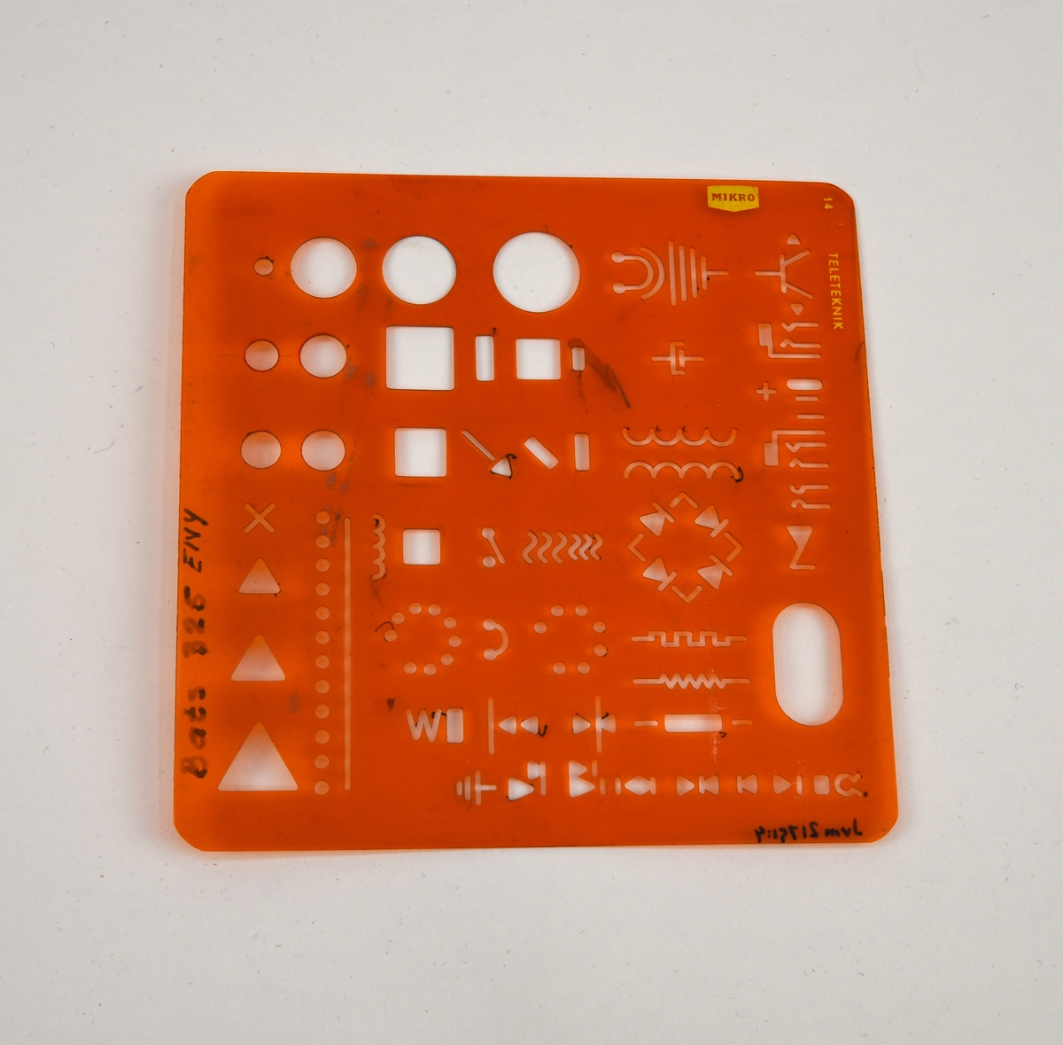 Ritningsmall för teleteknik av orange, genomskinlig halvmjuk plast. På mallen finns olika elektrotekniska symboler som diodbrygga, jordpunkt, motstånd, telejack och så vidare. Mallen är märkt "Bats 325 EIVY" i tusch.