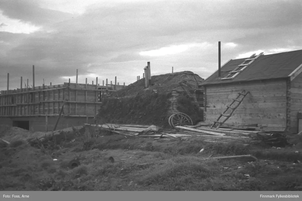 Diverse byggearbeider i Tanadalen, august-september 1946. Torvgamme mellom gjenreisningshus under bygningsarbeid og et lite hus.