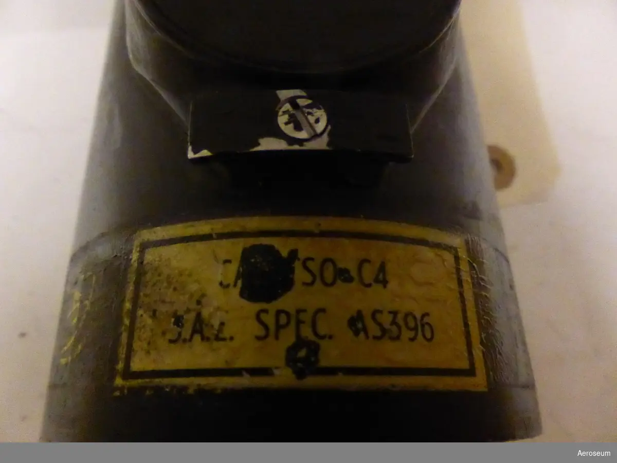 Gyrohorisont, tillverkad av Sperry Gyroscope Co. och är gjord i svart metall. På föremålet står det skrivet i gul text (ganska utsuddat): "JUN 19 1932". Det finns en trasig påtejpad ettikett där det står "CA [går inte att tyda]SO C4 [går inte att tyda].A.[går inte att tyda] SPEC. AS396". I botten finns det en ettikett där det står: "115 VOLTS [går inte att tyda]  CYCLES PART NO. 608588 - 2 - 13 SERIES NO. 2329B SPERRY GYROSCOPE CO. DIV. OF SPERRY RAND CORP. GREAT NECK N. Y. PATENT NO'S 2,409,659 - 2,452,473 - 2,485,552 OTHER PATENTS PENDING".

Det finns även en tejp där det står: "[trasig tejp] HNISCH Flygplansinstrumentverkstad [går inte att tyda]platsinfarten 6 - Bromma - SWEDEN [går inte att tyda] No: B02002 [går inte att tyda]PAIR [bortrivet, men troligtvis CON]NTROL Inspector's Pe NOV 63"