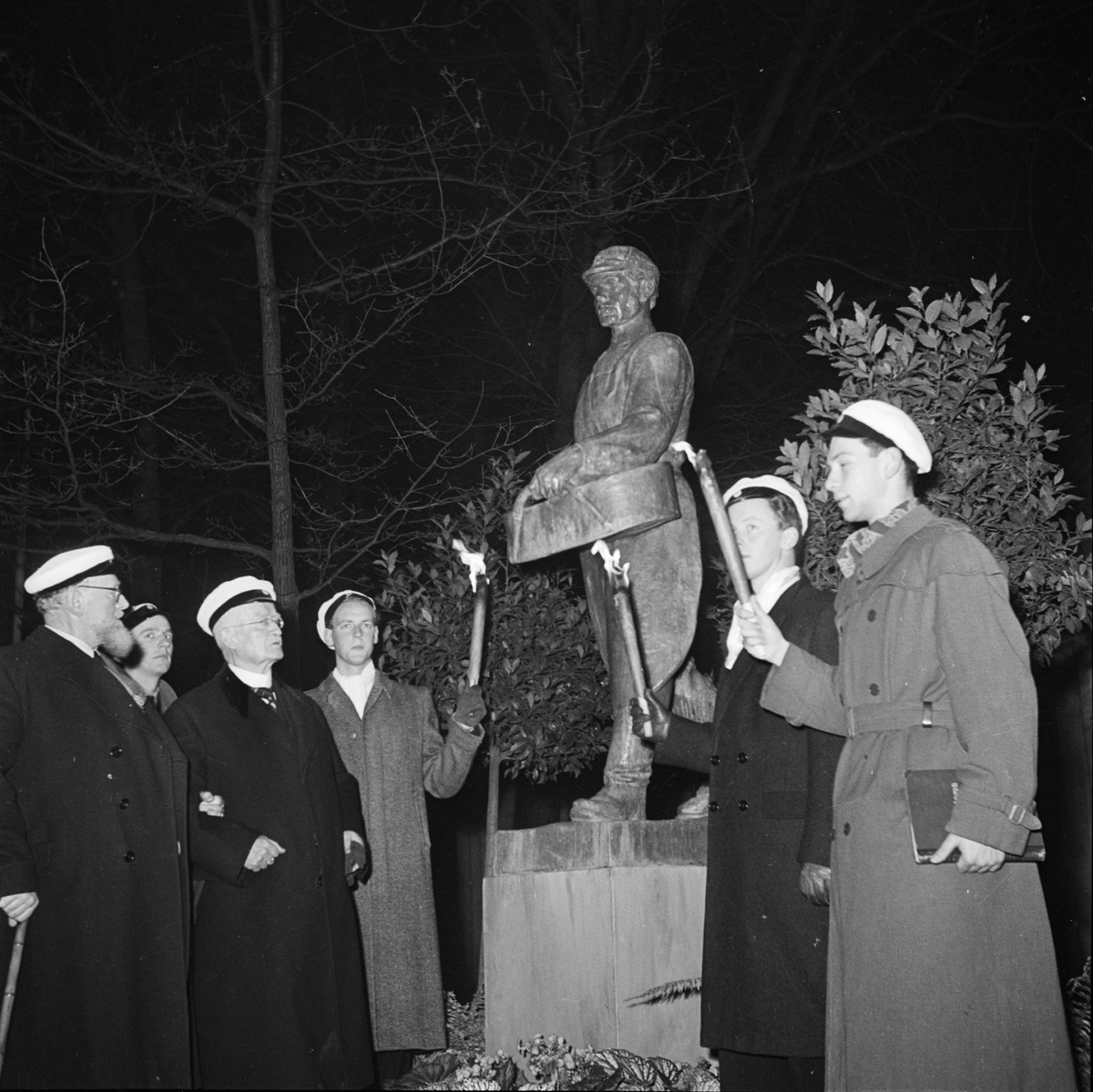 Män med studentmössor och facklor vid avtäckningen av skulpturen Såningsmannen. Längst till vänster skulpturens upphovsman konstnären Gottfrid Larsson. Östgöta nations 300-årsjubileum, Uppsala 1946