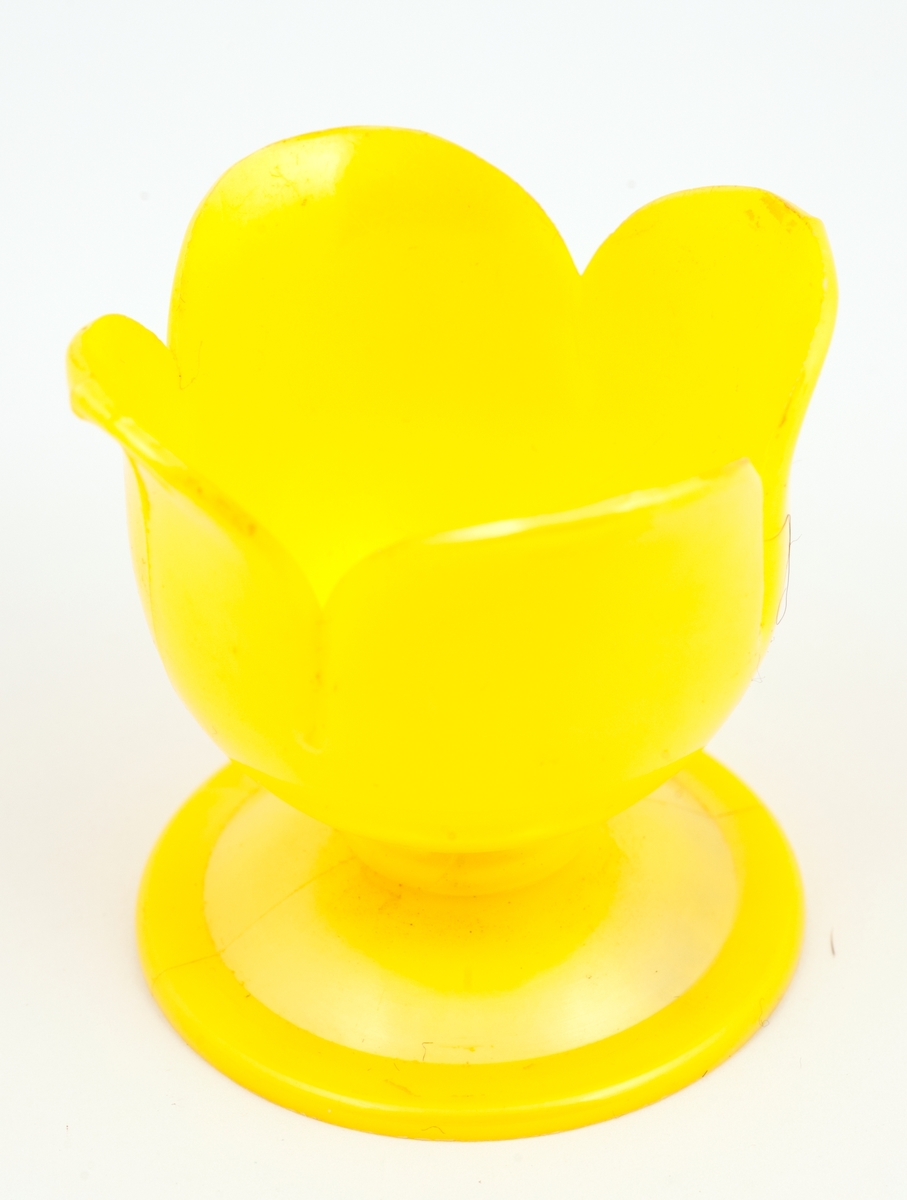 Gult eggeglass av plast med skålen formet som fire kronblad.