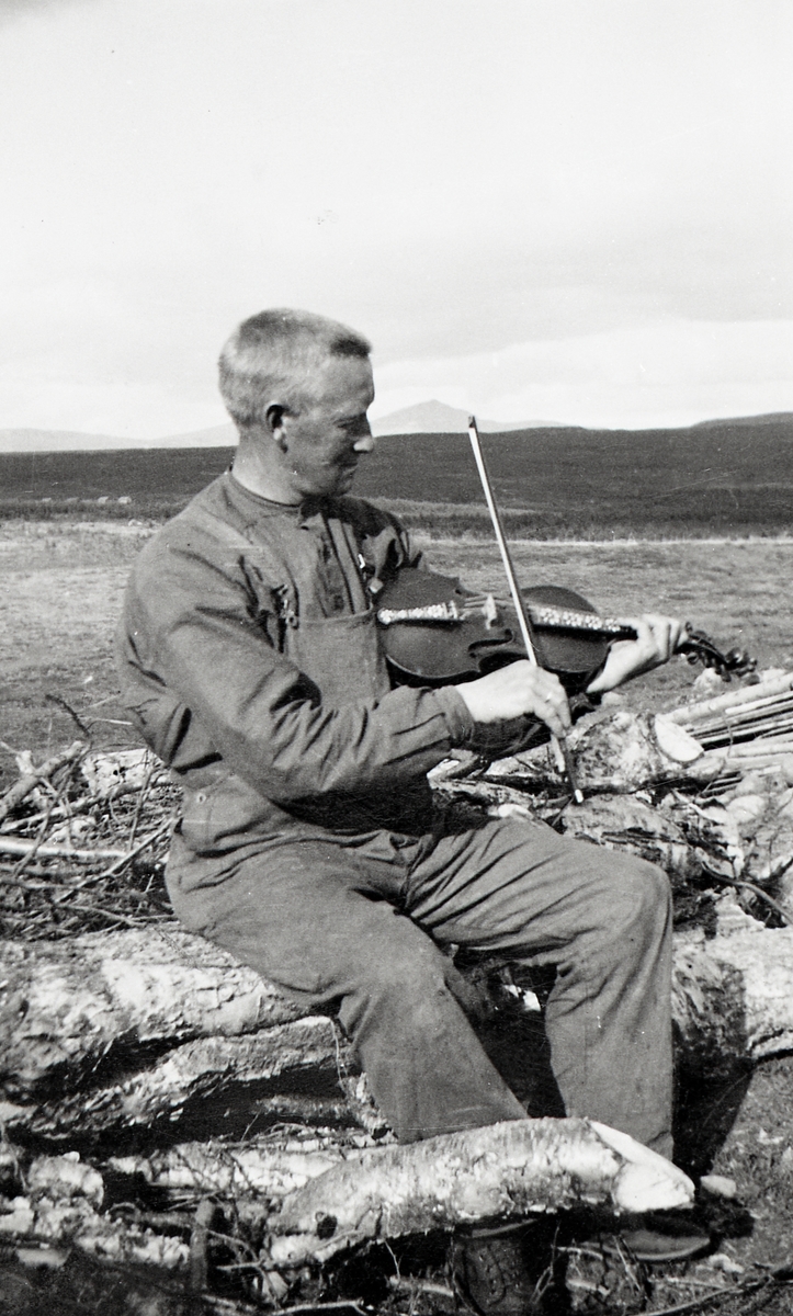 Ola Lie Haugen sit ute på stølsvollen og spelar ( Fetstølen) ca. 1940-1945.