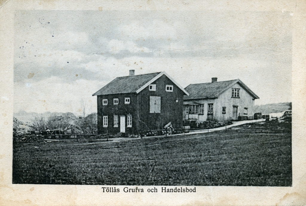 Vykort med motiv från Töllås Grufva och Handelsbod. Två byggnader med omkringliggande odlingslandskap.