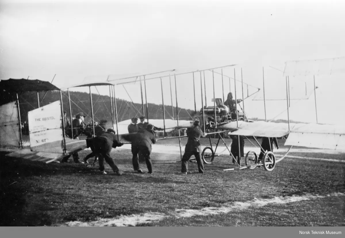 Den svenske løyntnant O. Dahlbeck med sitt Bristol biplan under start på Etterstad i Oslo
Flygeren sitter klar til start, syv menn holder i flyets hale