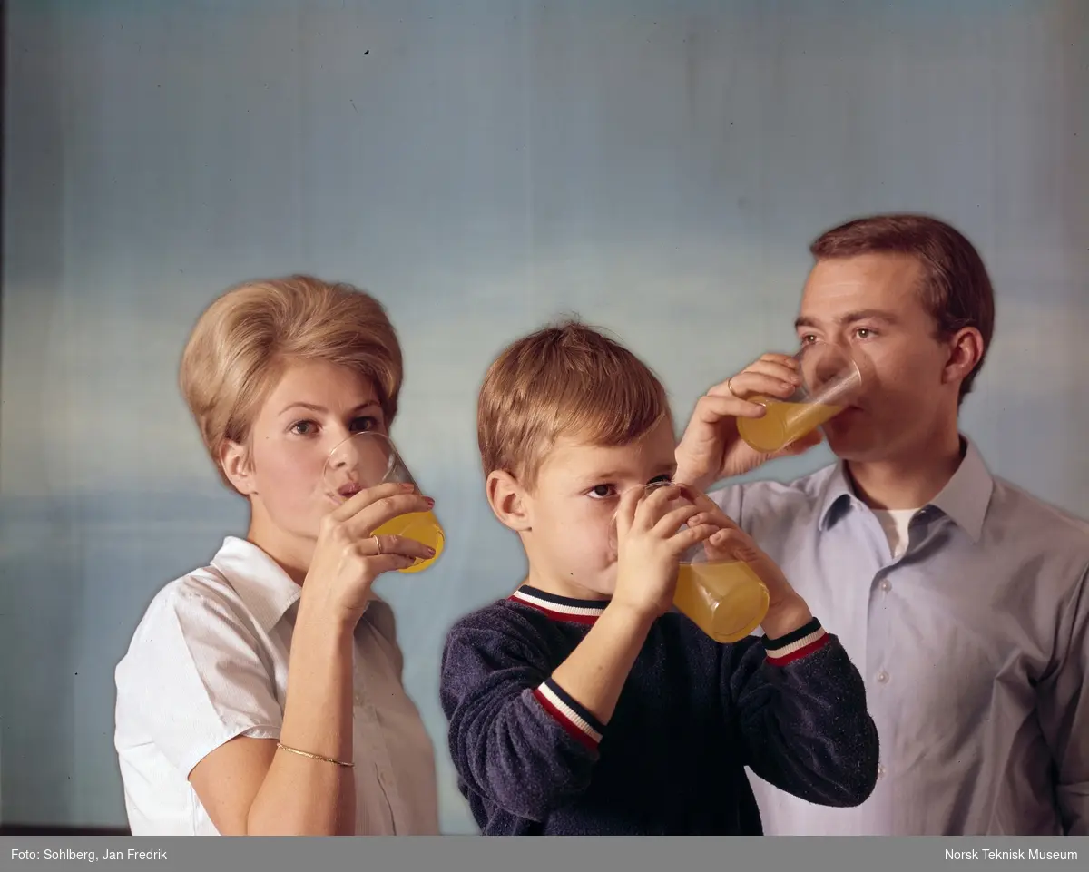 En kvinne, en mann og en gutt, drikker gul saft.
