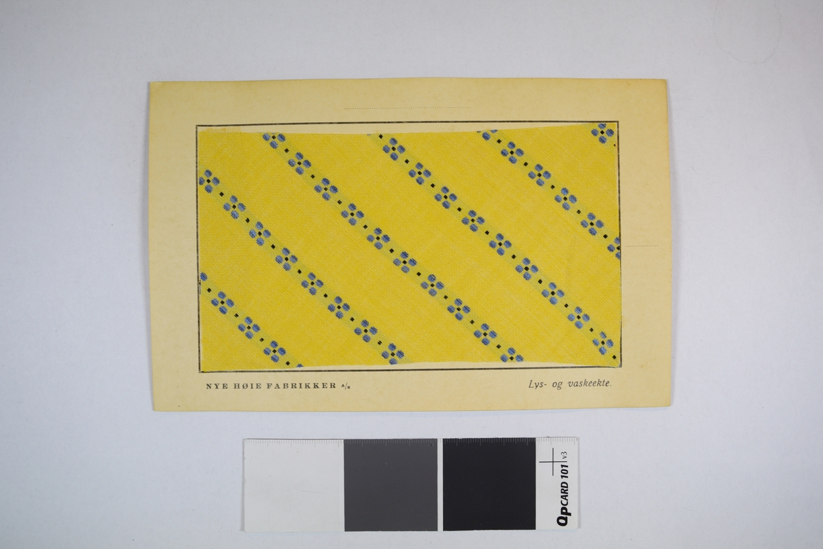 Prøvekort bestående av tekstilprøve limet til et papirkort. Prikkete mønster.