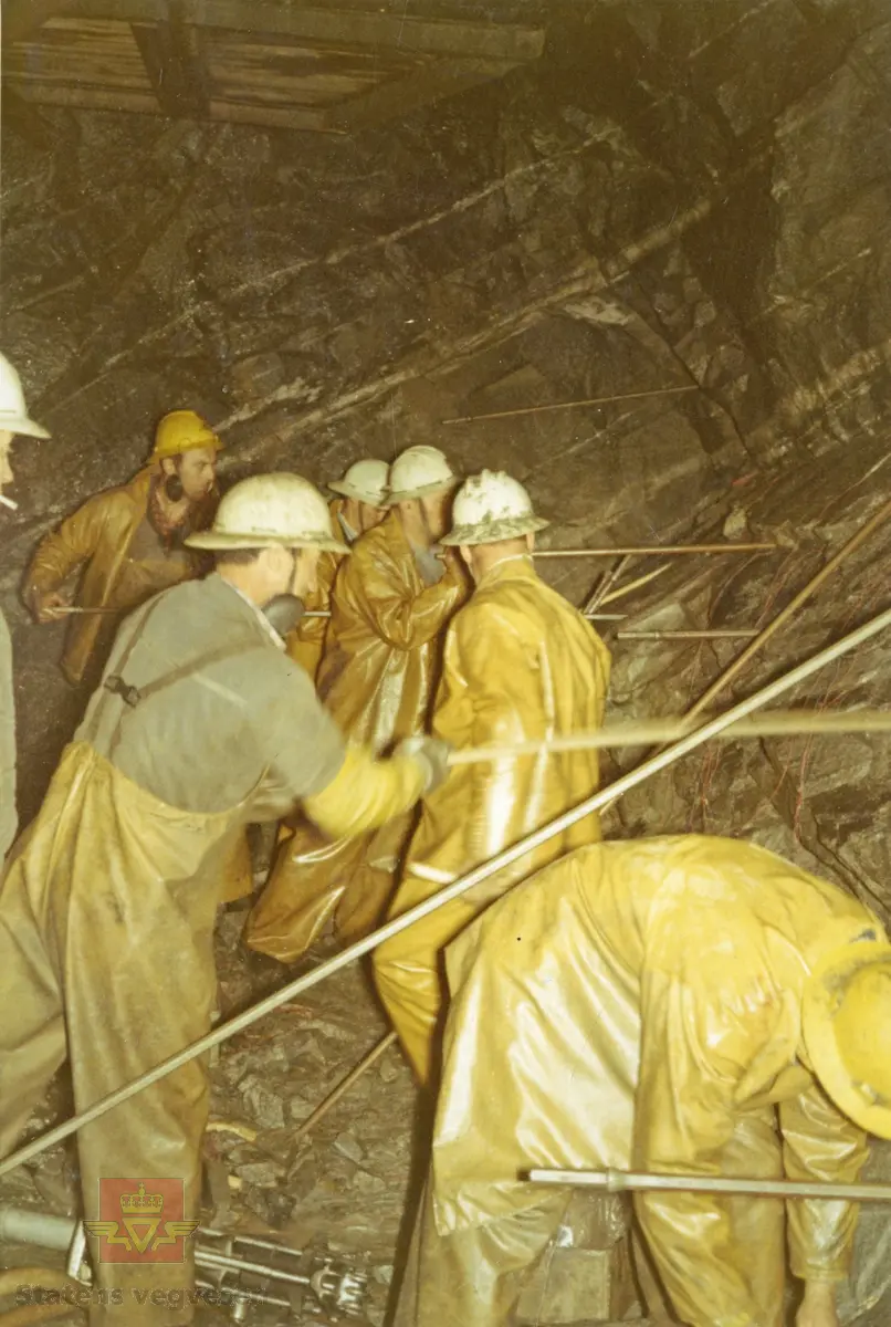7 mann i arbeid med lading av siste salve på Skaugvolltunnelen. Langs Kystriksvegen.