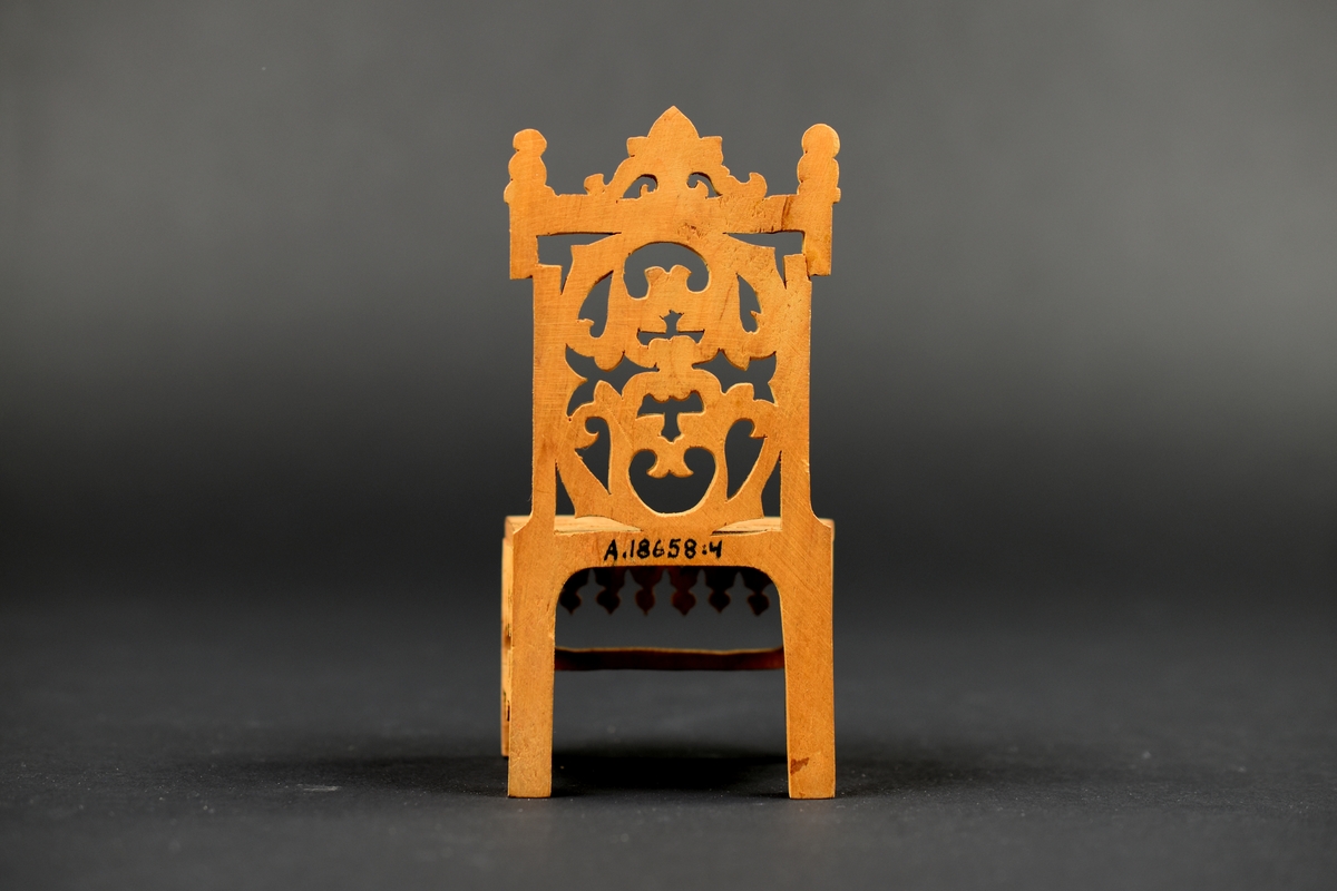 En av två stolar tillverkade av cigarrlåda, med genombruten dekor i sits, rygg och sarg.