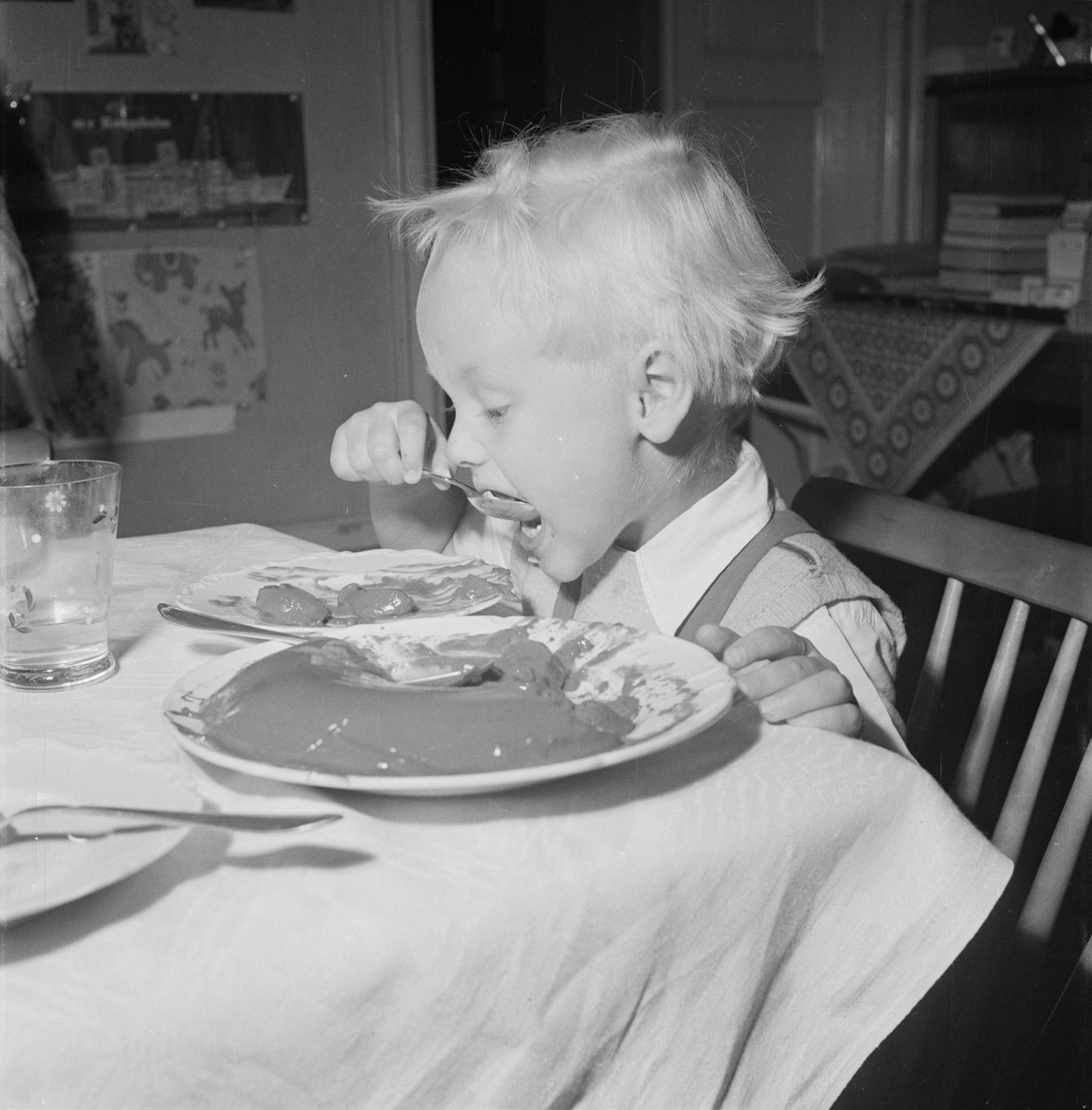 Pojke sitter vid matbord och äter, Uppsala 1954