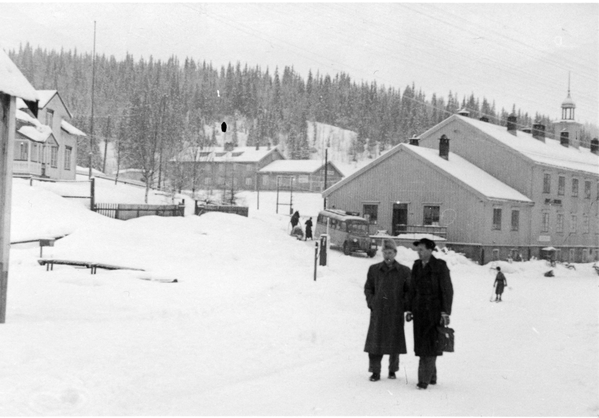 To menn oppstilt foran stor bygning vinters tid