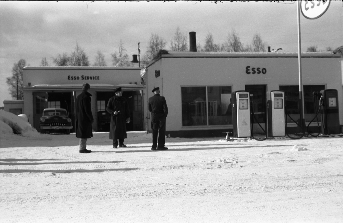 Tre bilder av noen mannfolk ved Esso benstinstasjonen på Lena februar 1958. Helt til høyre på alle tre bildene er muligens Torbrjørn Lundsten, drosjesjåfør fra Kraby, og til høyre for han muligens Paul Grindvoll.
Bilen i bakgrunnen er iflg. informant en drosjeregistrert De Soto årsm. 1951-53.