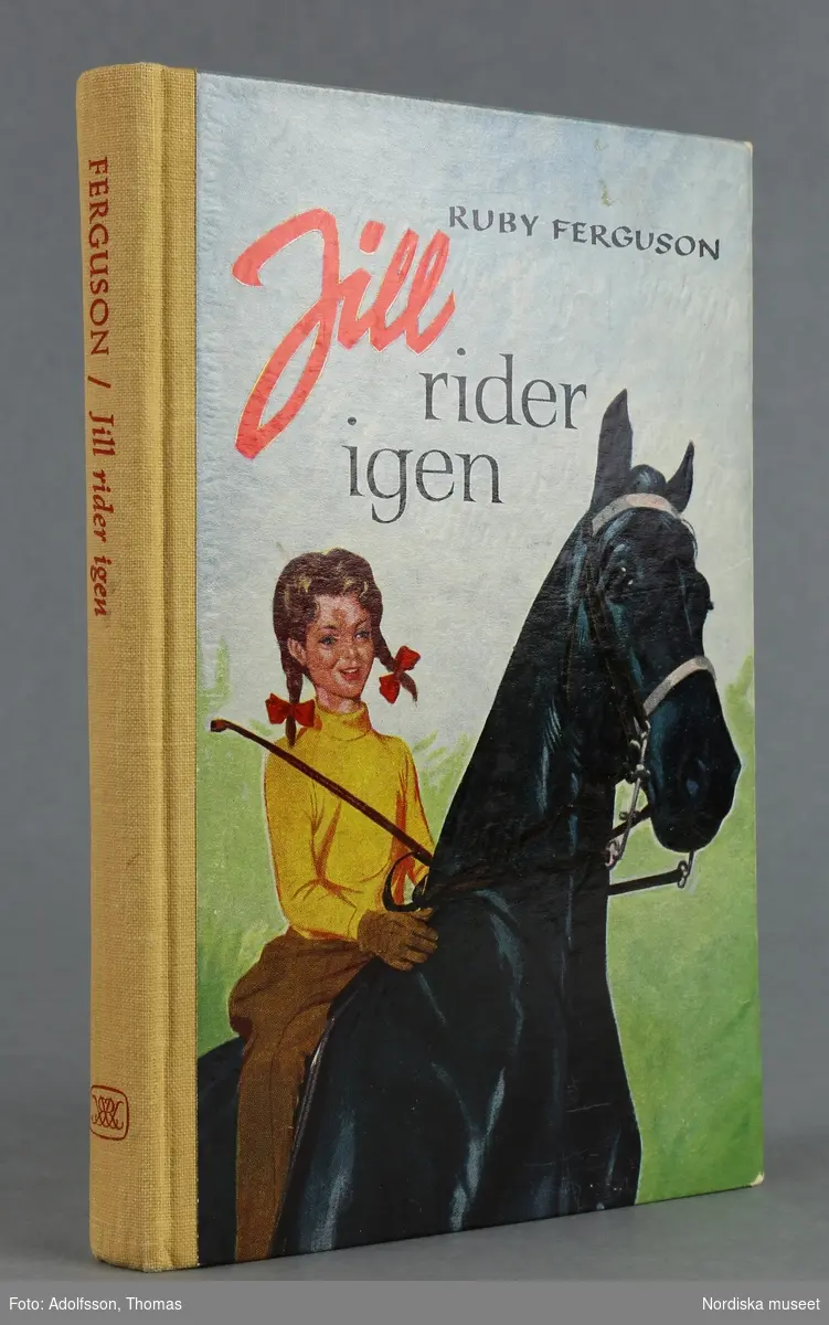 Flicka med ridspö rider på en svart häst.