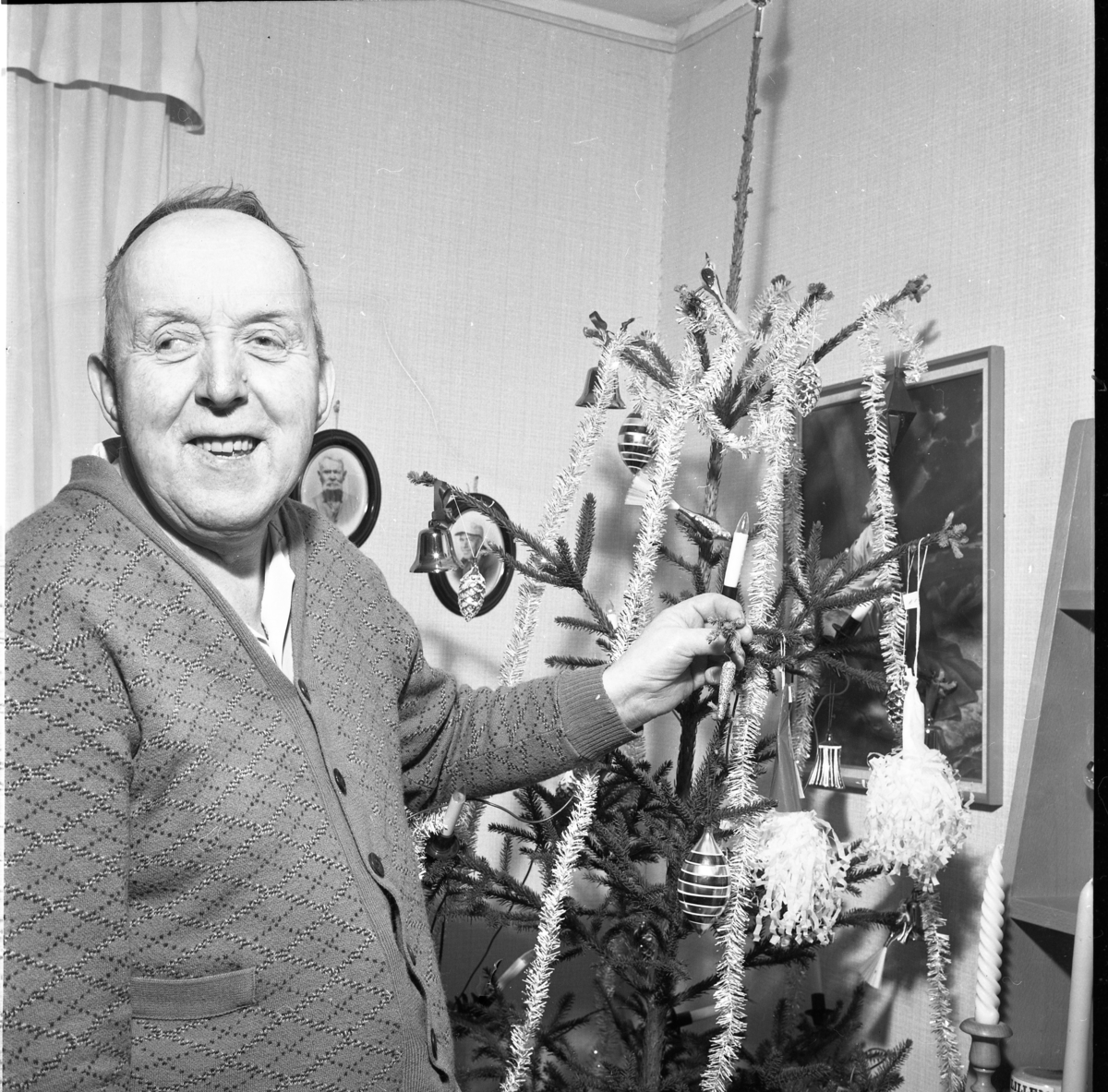 Fiskaren John Öhlander på Skärstadals ålderdomshem står intill en julgran. Han bär en mönstrad stickad kofta.