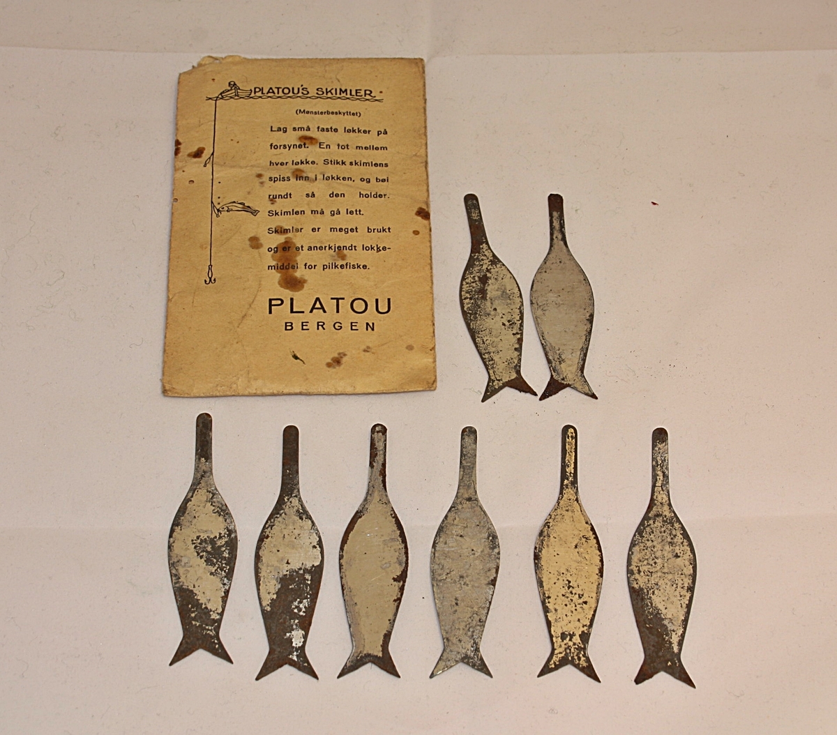 Rektangulær konvolutt innhaldane 8 stk små "skimler" som lokkemiddel for pilkefiske.