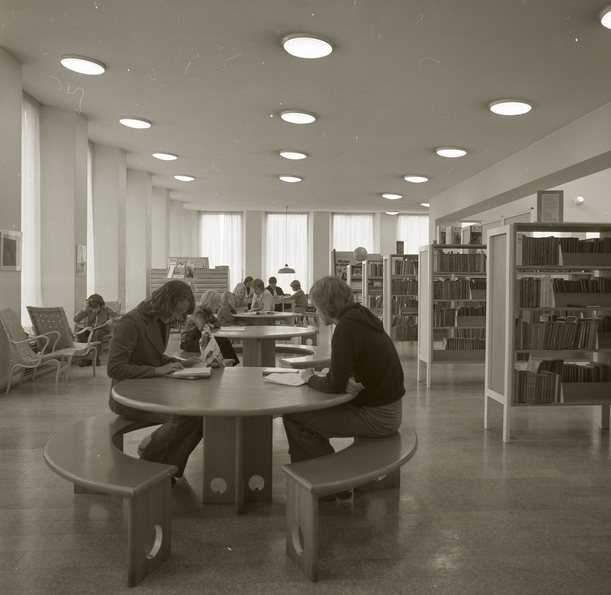 Några personer sitter och läser vid bord i Härnösands bibliotek, 1974.