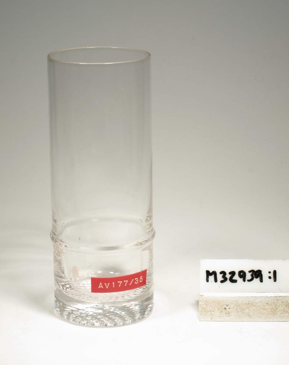 Cylindriskt glas med vulst på dess nedre del. Nätmönster i botten.
Lapp: "AV 177/45"