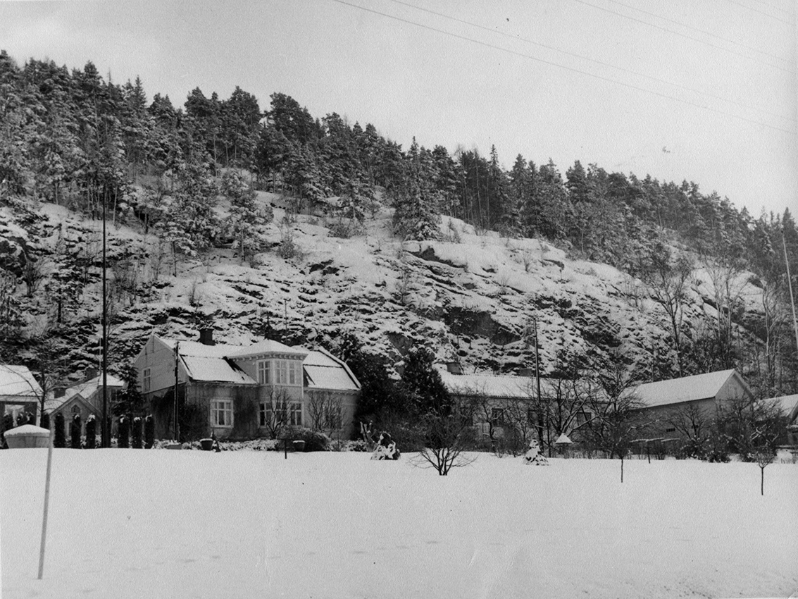 Bergsgatan i Gränna från nuvarande Braheparken mot kvarteren Vulcanus 2 och 3 med Grännaberget i bakgrunden. Det är vinter med snö på marken och på berget.