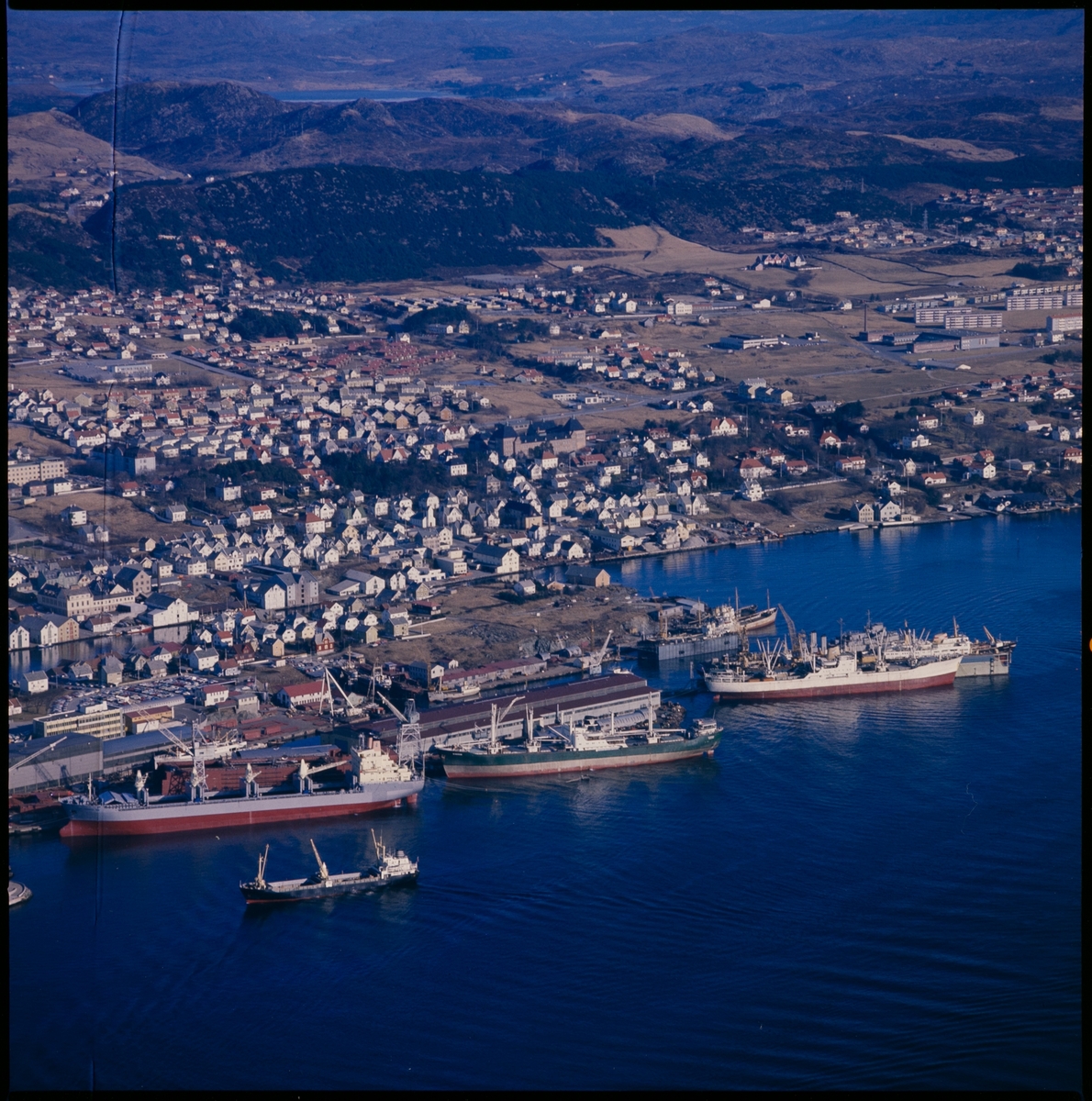 Flyfoto av Haugesund Mekaniske Verksted med Risøy og Haugesund i bakgrunnen. Det ligger flere store skip ved verftet.