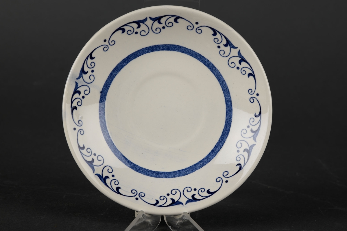 Hvit tallerken, dekorert med en blå sirkel i midten og blåe grener rundt kanten.