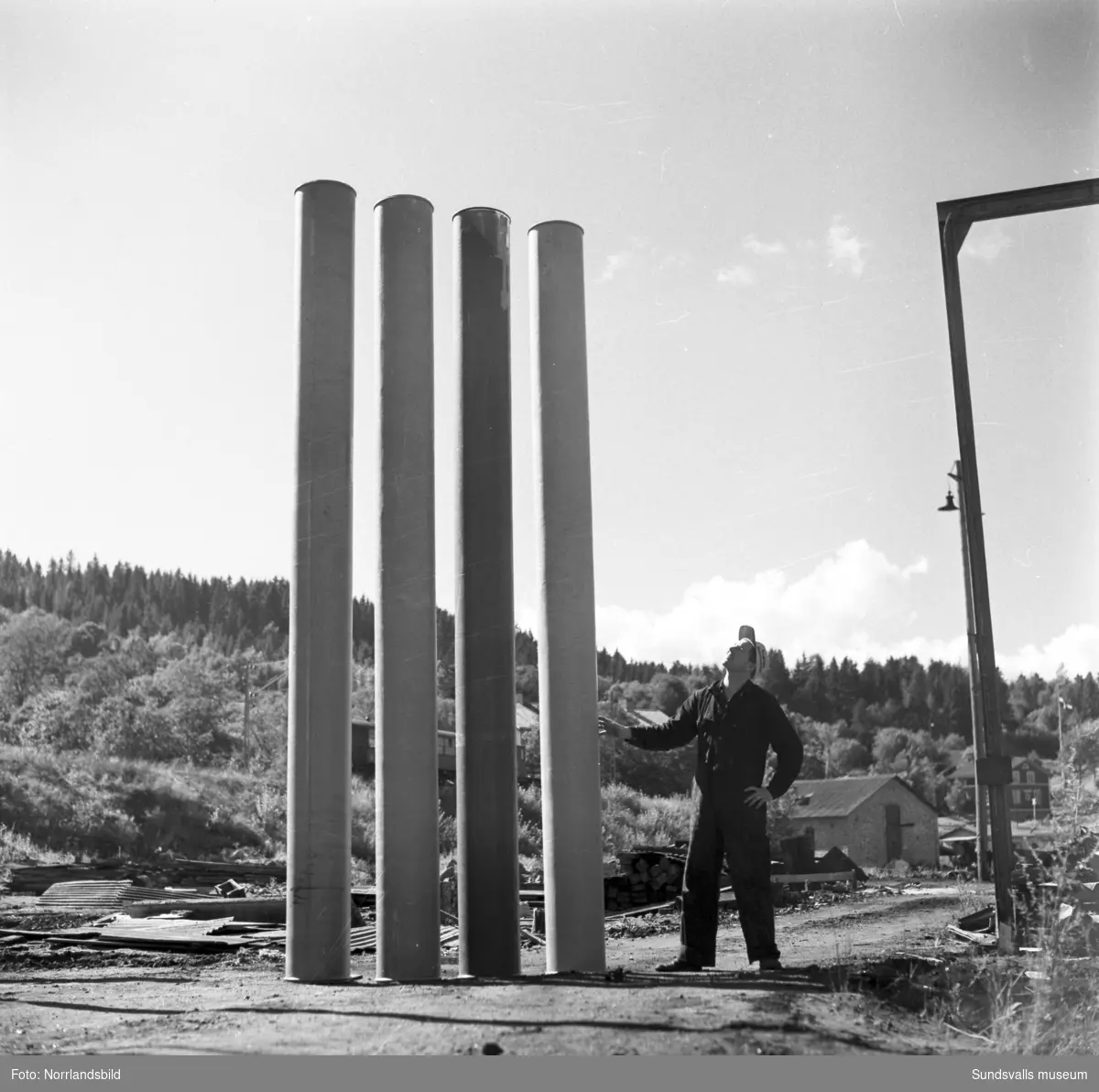 Firma Bertil Ericsson, Sundsvall (senare AB Centrifugalplast). Tre män sitter grensle över en stor plasttrumma, i bakgrunden en fabrik. Bild 2-3: en man som förevisar plasttrummor och bakom syns ett tåg. (Skönvik?)