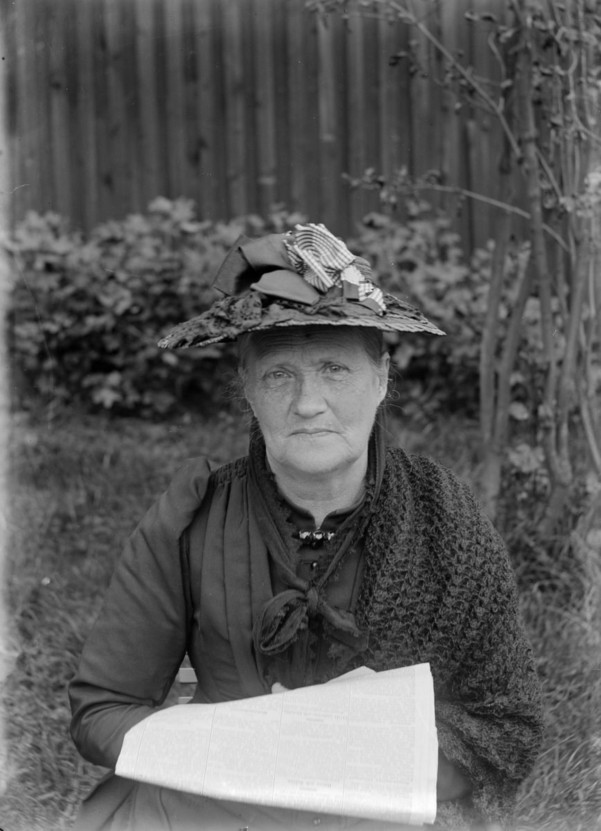Kvinna i hatt läsande tidning.