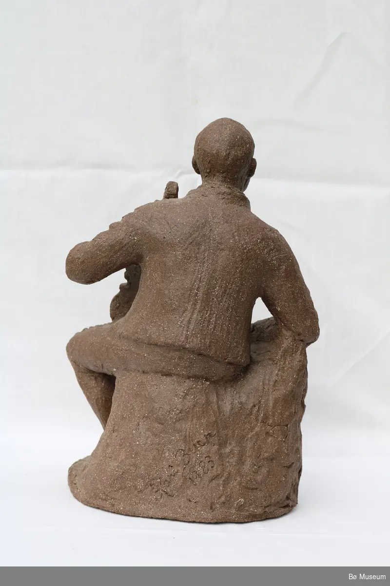 Statuen forestiller felespelaren Lars Fykerud sittande i folkedrakt mens han holder fela i venstre arm.